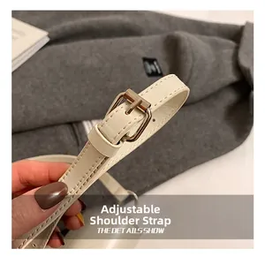 Detail of adjustable off-white leather strap with gold buckle on crossbody saddle bag