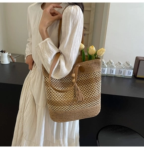 Detail of straw woven tote bag featuring hollow grid texture and brown leather strap