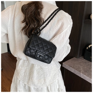 Detailed back view of a black quilted crossbody bag with silver chain strap on a model