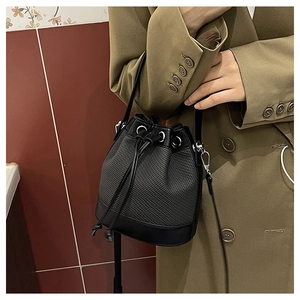 Détail du sac seau noir tressé avec cordon de serrage et garniture en cuir lisse