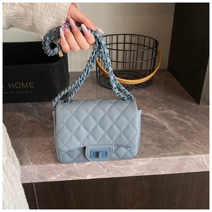 Detailed view of blue quilted crossbody bag with metal chain strap and turn-lock closure