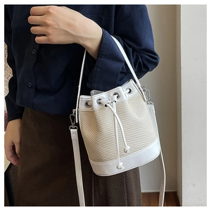 Détail du sac seau bicolore beige tissé avec finitions en cuir blanc et cordon de serrage