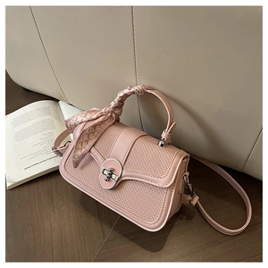 Detail of pink woven leather square handbag with silk scarf handle on wooden floor