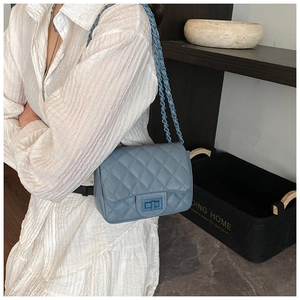 Close-up of blue quilted chain bag with turn-lock clasp and stylish metal chain strap