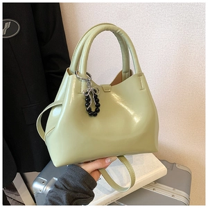 Detail of pistachio green leather handbag with beaded butterfly charm and round handle