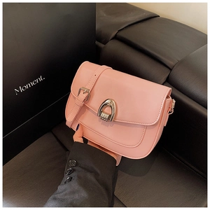 Detail of pink leather saddle bag featuring a silver horseshoe buckle and adjustable strap