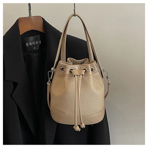 Détail du sac seau en paille avec garniture en cuir crème et fermeture à cordon coulissant