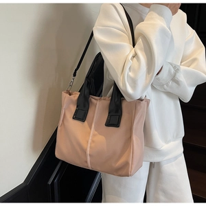 Detail of a pink crossbody bag with contrasting black straps and metal buckles on a model