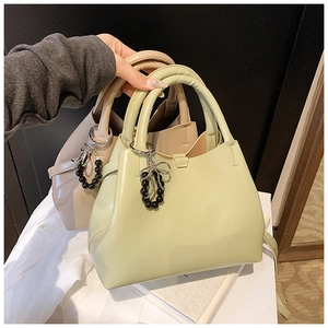 Detail of glossy patent leather handbags in mint and beige with chic beaded bow charms