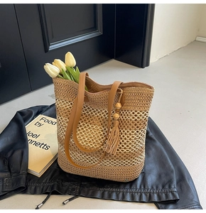 Detail of straw woven bag with leather straps and wooden bead tassel ornament