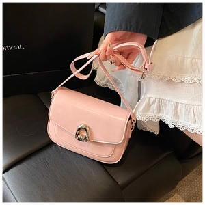 Detail of light pink saddle bag featuring silver U-shaped metal buckle and leather strap