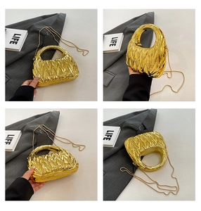 Detail view of a gold pleated acrylic handbag with metallic handle and chain strap