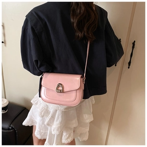 Rear view of a pink glossy saddle bag with metal horseshoe buckle worn over the shoulder