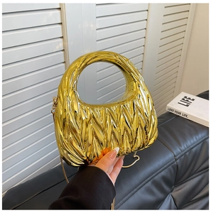 Detail of gold pleated cloud bag with metallic finish and round handle for evening wear