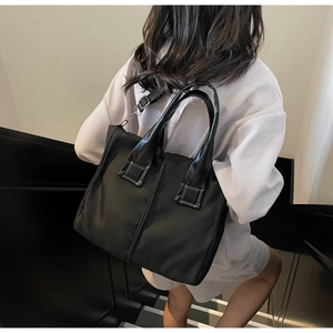 Side view of a black nylon tote bag shown on a model with adjustable crossbody strap
