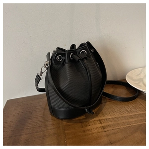 Détail d'un sac seau noir tissé avec garniture en cuir et ferrures métalliques argentées