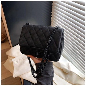 Detail of black quilted leather shoulder bag with caviar texture and metal turn-lock