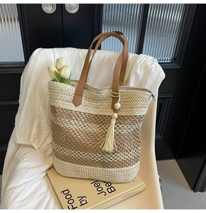 Detail of bohemian straw bag with woven stripe patterns and brown leather strap