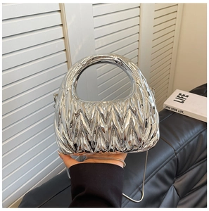 Close-up of silver crescent handbag with pleated texture and metal chain on a black sofa