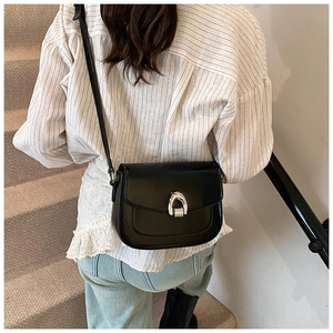 Street view of a black matte saddle bag featuring a large silver U-shaped metal buckle