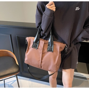 Detail of dark brown tote bag with contrast stitching and adjustable shoulder strap