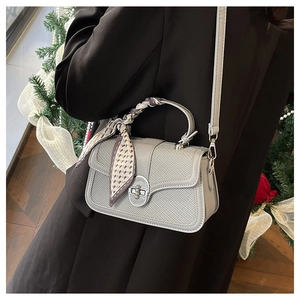 Detail of grey woven small square bag with silk scarf handle and metal twist lock