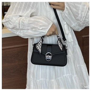 Close-up of black woven texture handbag with silver ring clasp and silk scarf detail