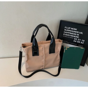 Detail of a two-tone tote bag with black straps and adjustable shoulder strap on a display