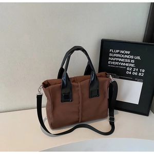 Detailed view of brown waterproof nylon tote bag with black straps and contrast stitching
