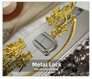 Macro detail of silver mirror evening bag with gold dragon accents and metal clasp