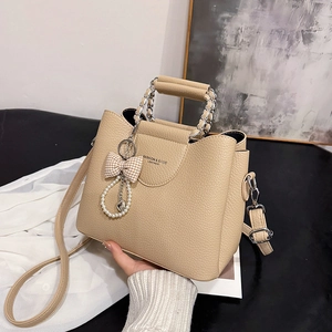 Beige lychee leather tote bag with chain handle, bow pendant and crossbody strap