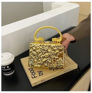 Detail of gold acrylic evening bag with fluid texture and dragon handle accents