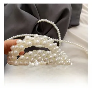 Détail de la poignée en perles tressées et de la doublure en satin de soie champagne