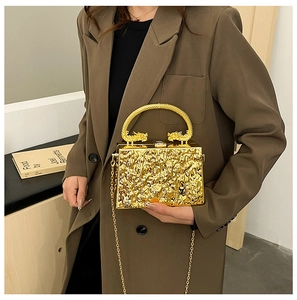 Detail of gold box clutch featuring liquid ripple texture and twin dragon metal handles
