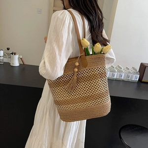 Handwoven straw tote bag with brown leather straps and tassel for beach vacation