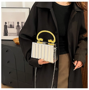 Detailed view of silver clutch bag with golden dragon handles and metallic chain