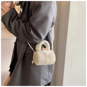 Vue détaillée du mini sac perlé avec poignée ronde sur fond de tailleur gris moderne