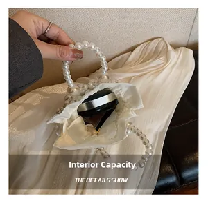 Détail montrant la capacité interne du sac à main à perles blanches avec maquillage