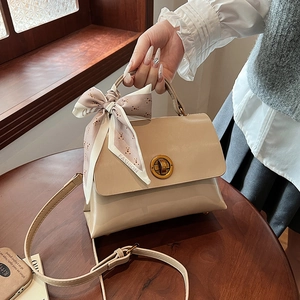 Detail of beige shoulder bag with gold twist lock and printed fashion silk scarf
