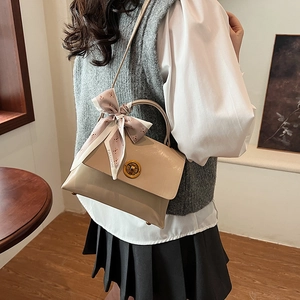 Detail of beige glossy handbag featuring a pink floral scarf and metal twist lock