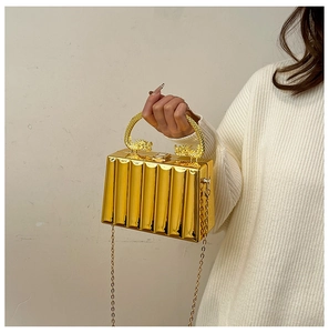 Detail of golden acrylic clutch bag with wave texture and ornate dragon-shaped handle