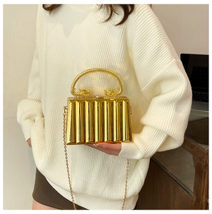 Detail view of golden evening bag featuring ornate dragon handles and ribbed texture