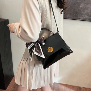 Side view of shiny black vintage shoulder bag with golden lock and fashion scarf detail