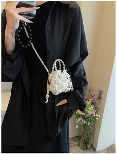 Détail d'un sac seau en perles fait main avec pochette en satin et bandoulière chic
