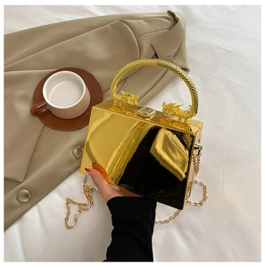 Detail of gold mirror evening bag with decorative dragon handle and metal chain