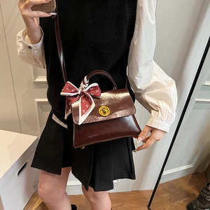 Detail of vintage dark brown patent leather bag with silk scarf and gold twist lock