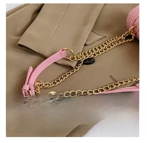 Detail of pink leather strap with gold chain and hardware on a quilted handbag