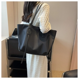 Détail d'un grand sac cabas noir porté par un mannequin dans un bureau minimaliste