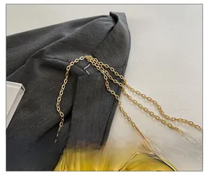 Macro detail of golden mirror textured bag with multi-strand metallic chain strap