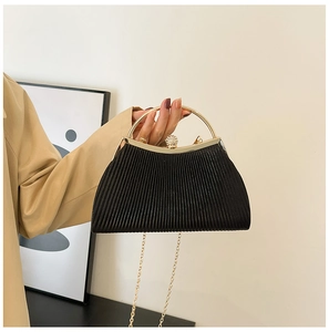 Detail of black pleated evening bag featuring a gold metal handle and crystal clasp